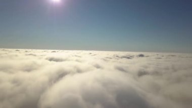 Parlak güneşli bir günde, beyaz kabarık bulutların yukarıdan görünüşü.