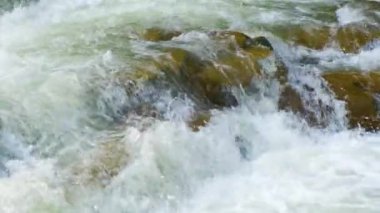 Berrak turkuaz suyu olan dağ nehri, kalın beyaz köpüklü ıslak kayaların arasına dökülüyor..