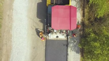 Çalışan işçiler ve asfalt döşeyen makinelerle yeni yol yapımının havadan görünüşü