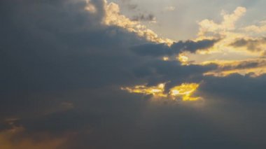 Günbatımında sarı gökyüzünde hızlı hareket eden akşam bulutlarının hızlandırılmış görüntüleri.