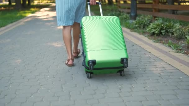 年轻女子提着绿色手提箱走在城市街道人行道上 旅行和度假概念 — 图库视频影像