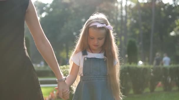 ママと娘の子供一緒に夏の公園で手をつないで歩く — ストック動画