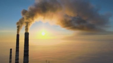 Kömür santralinin hava manzarası siyah dumanlı yüksek borular gün batımında atmosferi kirletiyor.