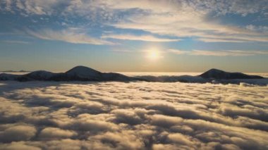 Ufuktaki Karpat dağlarının uzak karanlık zirveleriyle beyaz yoğun sis üzerinde canlı gün doğumunun havadan görüntüsü.