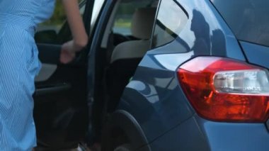 Şehir caddesinde yeşil bavulu arabadan çıkaran genç bir kadın sürücü. Seyahat ve tatil kavramı.