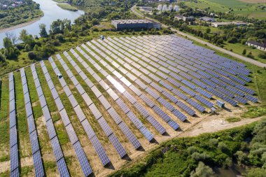 Yeşil alandaki güneş enerjisi santralinin havadan görüntüsü. Temiz ekolojik enerji üretmek için panelleri olan elektrik çiftliği.