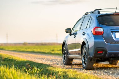 Çakıl yolunda mavi off-road arabalı manzara. Otomobille seyahat, vahşi yaşam macerası, keşif gezisi ya da bir SUV otomobili ile aşırı seyahat. Offroad 4x4 aracı gün doğumunda arazide olacak..