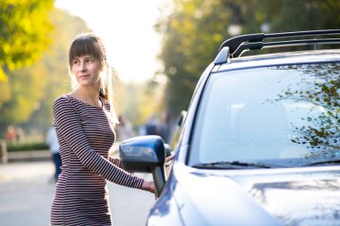 Genç bayan sürücü arabasının yanında dinleniyor sıcak yaz gününün tadını çıkarıyor. Seyahat ve kaçış konsepti.
