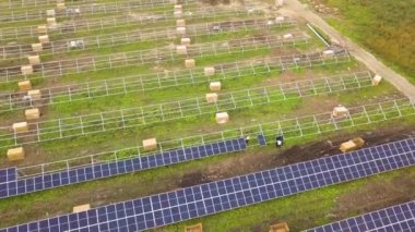 Yeşil alanda inşa halindeki güneş enerjisi santralinin havadan görüntüsü. Temiz ekolojik enerji üretmek için elektrik panellerinin montajı.