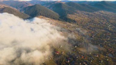Gün doğumunda dağ tepelerini ve köy evlerini kaplayan sisli bulutlardan oluşan canlı bir manzara..