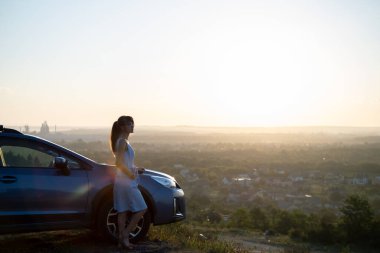 Mavi elbiseli mutlu genç kadın şoför sıcak yaz gününün tadını çıkarıyor. Seyahat ve tatil kavramı.