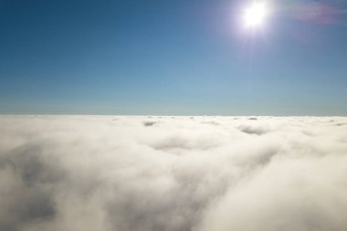 Parlak güneşli bir günde, beyaz kabarık bulutların yukarıdan görünüşü.
