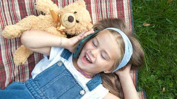 Hübsches Mädchen Liegt Mit Ihrem Teddybär Auf Dem Grünen Rasen — Stockfoto