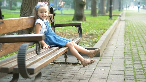 Küçük Mutlu Bir Kız Çocuğu Yaz Parkında Bir Bankta Dinleniyor — Stok fotoğraf