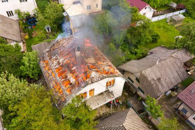 Aerial view of a house on fire with orange flames and white thick smoke. clipart