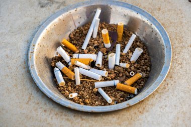 Sokakta sigara izmaritlerini metal kül tablasında kapatın. Sigara içtikten sonra çok sayıda sigara kalıntısı kavramı.