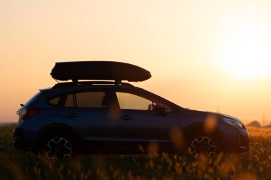 Gün batımında yol kenarına park edilmiş arazi aracı bagaj konteynırlı arazi aracı..