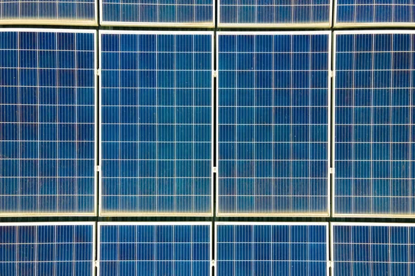 Aerial view of surface of blue photovoltaic solar panels mounted on building roof for producing clean ecological electricity. Production of renewable energy concept.