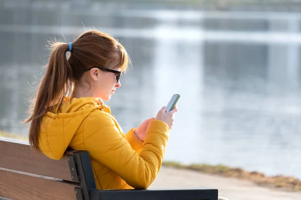 Молодая Красивая Женщина Сидящая Скамейке Парке Просматривает Свой Телефон Открытом — стоковое фото
