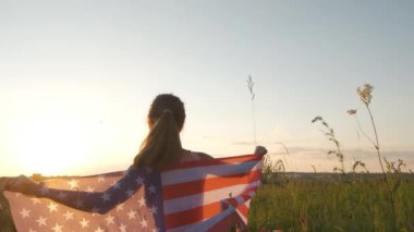 Gün batımında Amerikan bayrağıyla dışarıda oturan mutlu kadının arka görüntüsü. Amerika 'nın bağımsızlık gününü kutlayan pozitif kız. Uluslararası Demokrasi Günü.