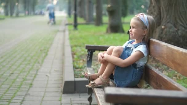 Küçük Mutlu Bir Kız Çocuğu Yaz Parkında Bir Bankta Dinleniyor — Stok video