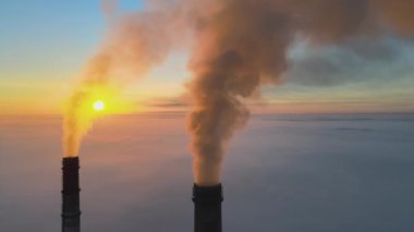 Kömür santralinin hava manzarası siyah dumanlı yüksek borular gün batımında atmosferi kirletiyor.