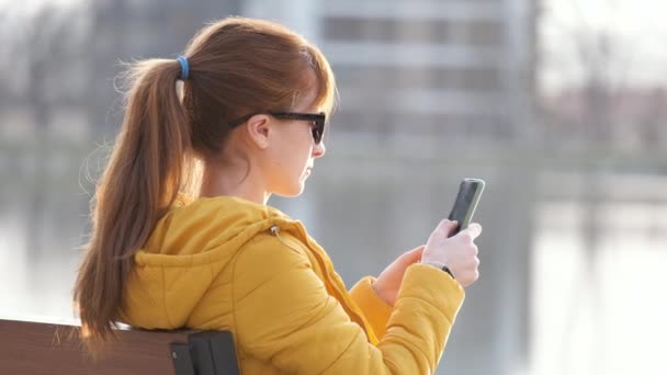 Jovem Mulher Bonita Sentada Banco Parque Falando Seu Smartphone Livre — Vídeo de Stock