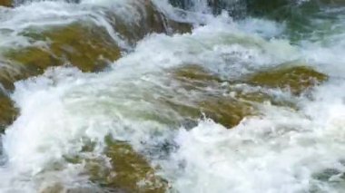 Berrak turkuaz suyu olan dağ nehri, kalın beyaz köpüklü ıslak kayaların arasına dökülüyor..