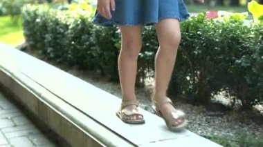 Güneşli bir günde yeşil yaz parkında yürüyen uzun saçlı güzel bir kız çocuğu..