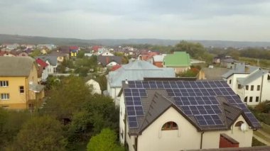 Çatıda temiz elektrik üretmek için güneş fotovoltaik panelleri olan özel bir evin havadan görüntüsü. Özerk konut kavramı.