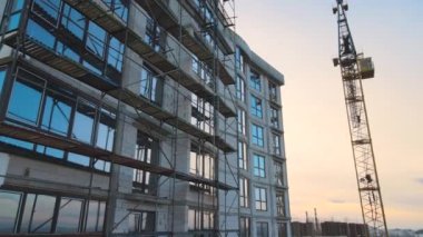 Aerial view of high tower crane and residential apartment building under construction. Real estate development.