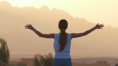 Sıcak ve güneşli bir akşamda, dağ manzarasının tadını çıkaran genç ve mutlu bir turist. Yaz tatilleri ve seyahat konsepti.