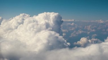 Parlak güneşli bir günde beyaz bulutların uçak penceresinden hava manzarası.
