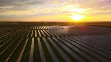 Günbatımında temiz ekolojik elektrik enerjisi üretmek için sıra sıra güneş fotovoltaik panelleri olan sürdürülebilir büyük elektrik santralinin havadan görünüşü. Sıfır emisyon kavramı ile yenilenebilir elektrik.