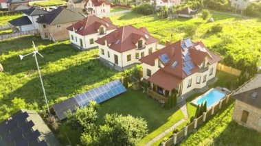 Çatıda güneş panelleri ve temiz ucuz elektrik üretmek için rüzgar jeneratörü olan otonom bir evin havadan görüntüsü..