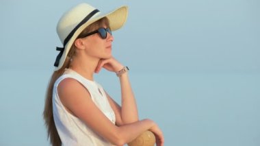 Sıcak bir yaz günü, deniz kenarında rahat rahat giyinen genç bir kadın..