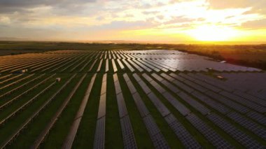 Günbatımında temiz ekolojik elektrik enerjisi üretmek için sıra sıra güneş fotovoltaik panelleri olan sürdürülebilir büyük elektrik santralinin havadan görünüşü. Sıfır emisyon kavramı ile yenilenebilir elektrik.