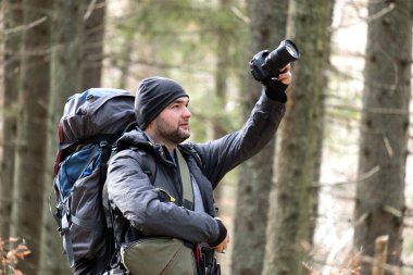 Sırt çantalı fotoğrafçı dijital fotoğraf makinesiyle doğanın fotoğraflarını çekiyor..