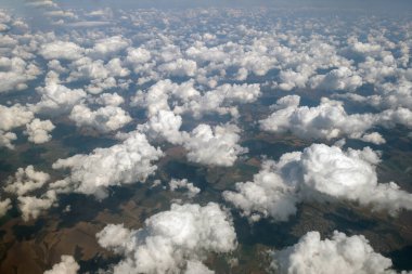 Parlak güneşli bir günde beyaz bulutların uçak penceresinden hava manzarası.