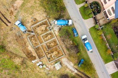 Kırsal yerleşim alanındaki yeni ev beton temeli inşaatlarının havadan aşağı manzarası.