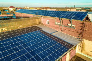 Mavi fotovoltaik güneş panelleri endüstriyel binaların çatısına temiz ekolojik elektrik üretmek için monte edildi. Yenilenebilir enerji konsepti üretimi.