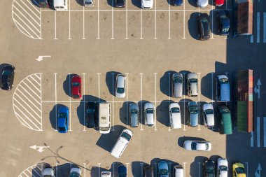 Otoparkta park yerleri ve yönler için çizgiler ve işaretlerle park edilmiş birçok renkli arabanın hava manzarası..
