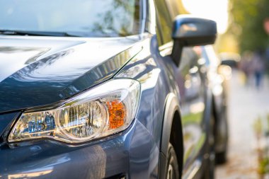 Şehrin cadde tarafında park edilmiş yeni temiz arabanın ön farının önü..