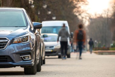 Bulanık insanların yaya bölgesinde yürüdüğü cadde kenarına park etmiş arabalar..