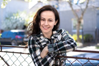 Güneşli bahar gününde mutlu bir şekilde gülümseyen güzel genç bir kadının portresi..