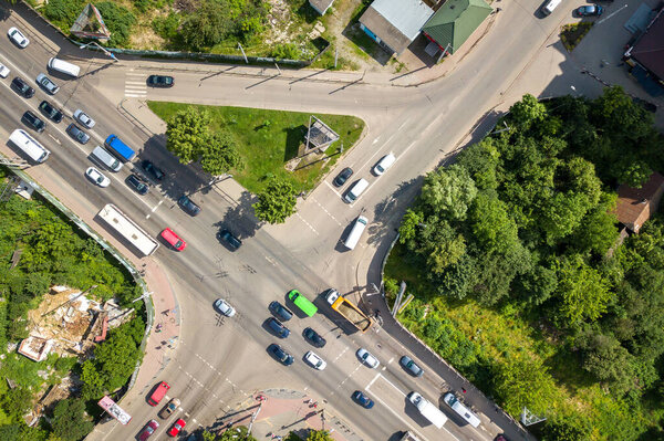 Top down aerial view of busy street intersection with moving cars traffic.