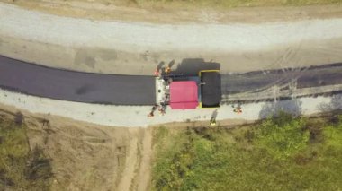 Çalışan işçiler ve asfalt döşeyen makinelerle yeni yol yapımının havadan görünüşü