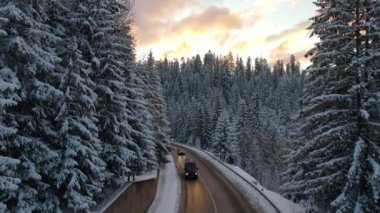 Kış manzaralı, karla kaplı dağ tepeleri ve dolambaçlı orman yolu..