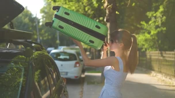 車の屋根のラックから緑のスーツケースを取り出し 街の通りを歩く若い女性観光客 旅行と休暇のコンセプト — ストック動画