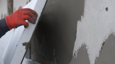 İnşaat işçisi termal koruma için evin ön cephesine köpük yalıtım çarşafları yerleştiriyor..